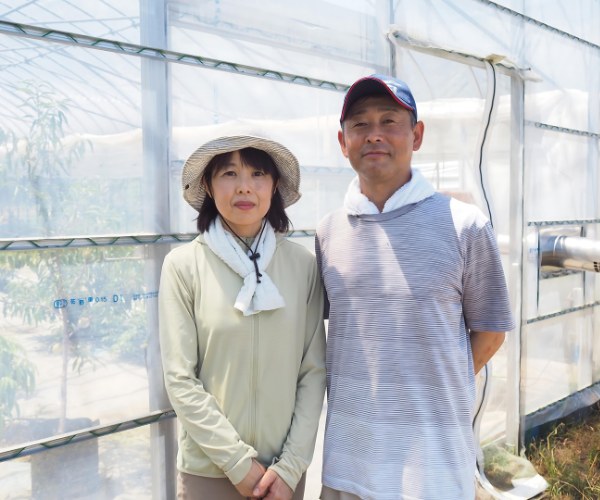 栽培ハウスの前に並んで立つ La.Aichi Farm のご夫婦
